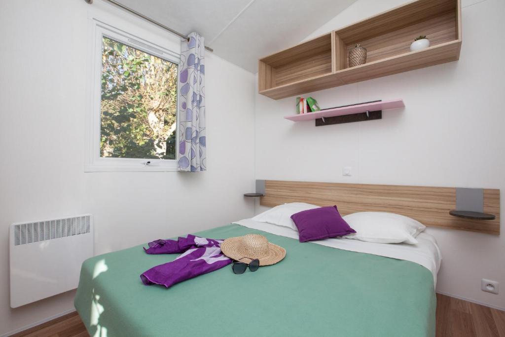 une chambre avec un lit avec un chapeau dessus dans l'établissement Camping Le Paradis, à Talmont-Saint-Hilaire 37 autres photos