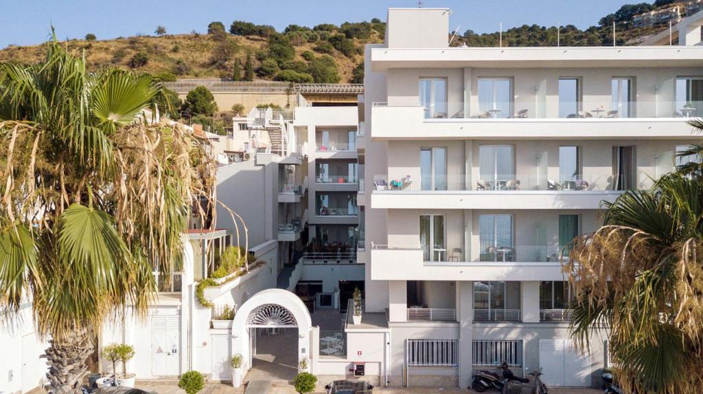 un bâtiment blanc avec des palmiers devant dans l'établissement Albatros Beach Hotel, à Letojanni