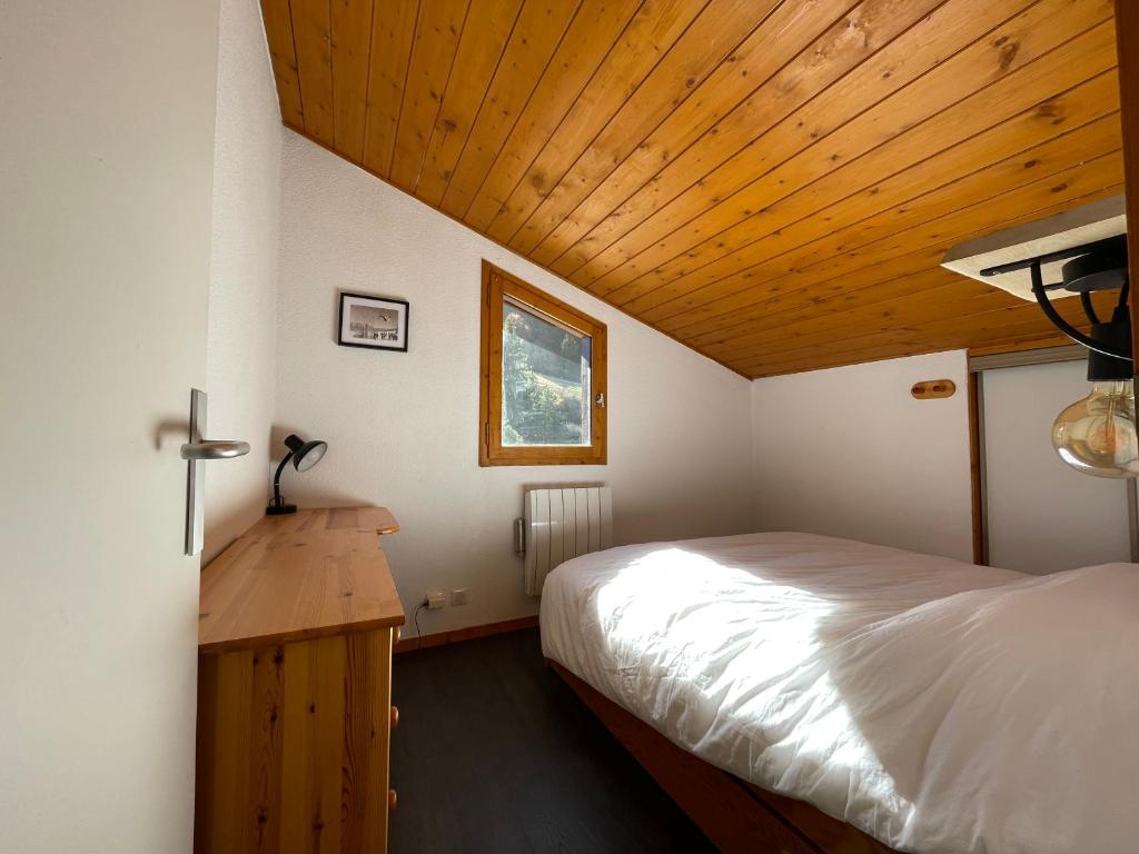 une chambre avec un lit et un plafond en bois dans l'établissement Duplex - Plein sud - Pied des pistes - 50m2 - Mottaret, à Les Allues