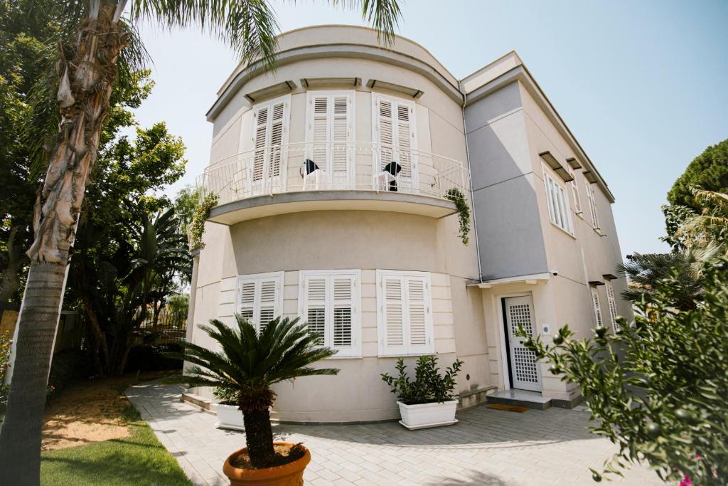 une grande maison blanche avec un palmier devant dans l'établissement Villa Calipso, à Mondello