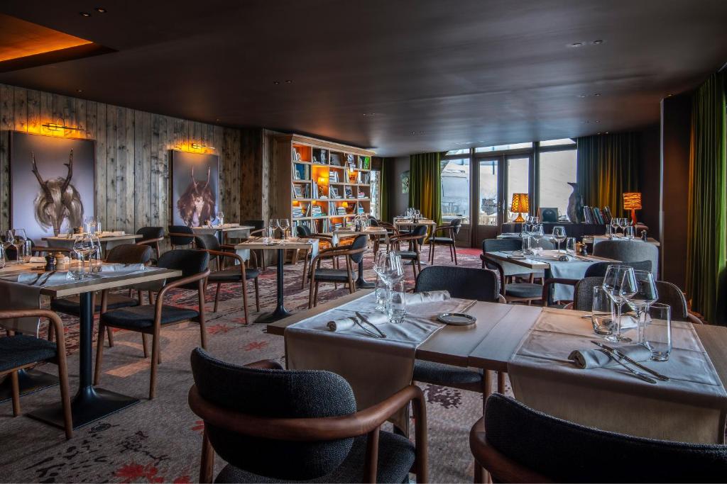 un restaurant avec des tables, des chaises et des fenêtres dans l'établissement Chalet Hotel Kaya, aux Menuires