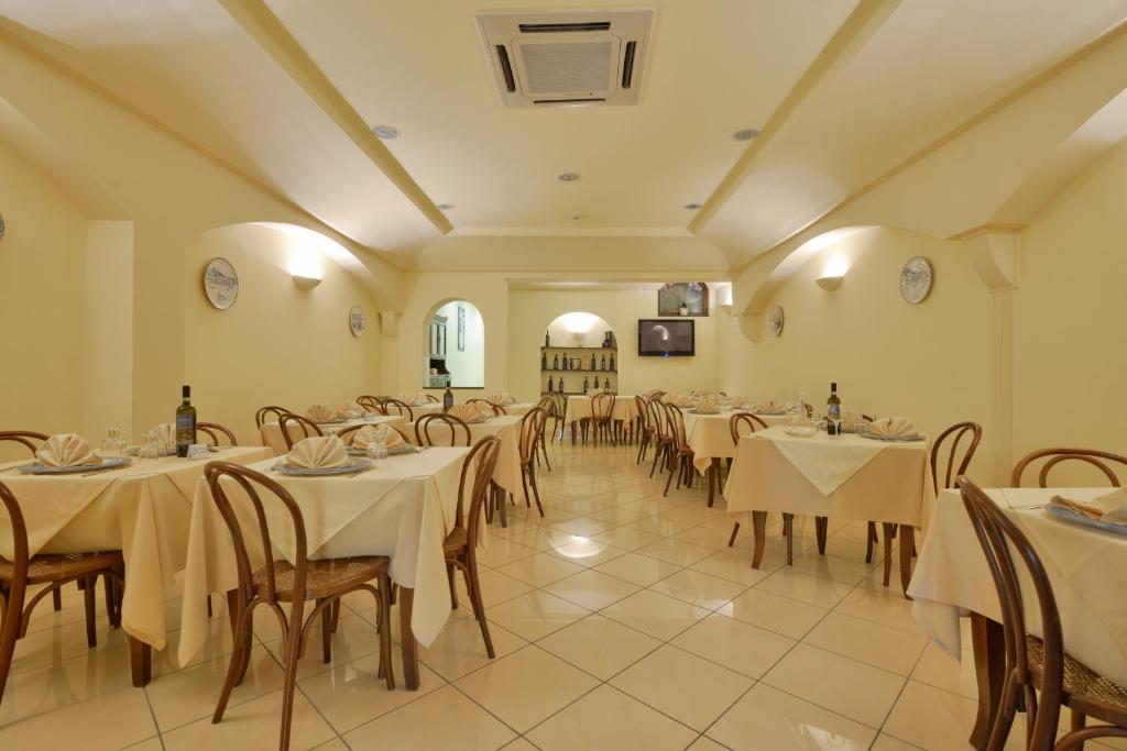 un restaurant avec des tables et des chaises avec une nappe blanche dans l'établissement Hotel La Marina, à Santa Maria di Castellabate