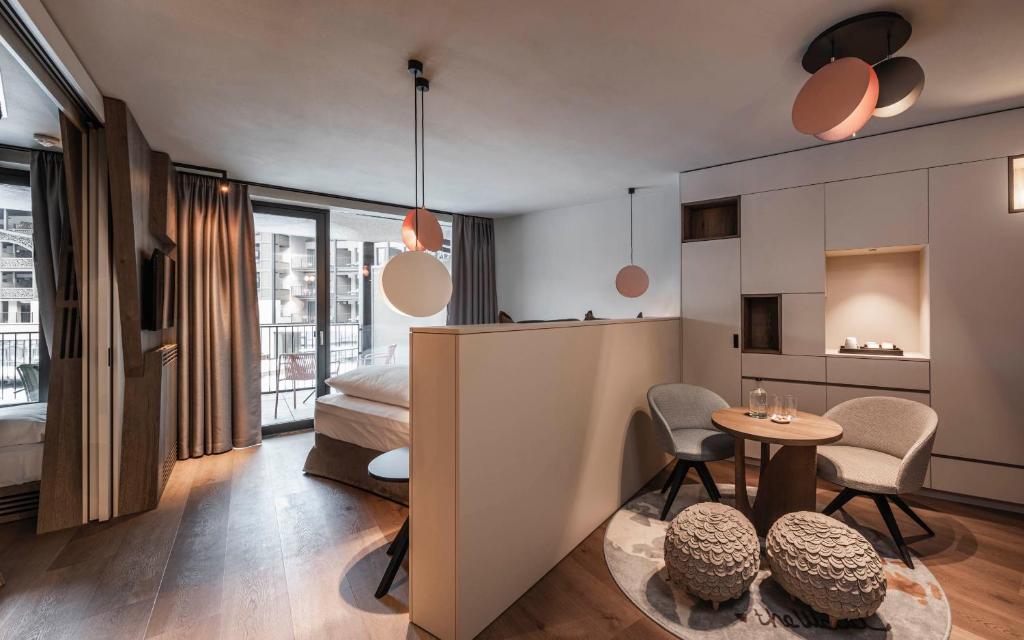 une chambre avec un lit, une table et des chaises dans l'établissement Falkensteiner Family Resort Lido Superior, à Chienes