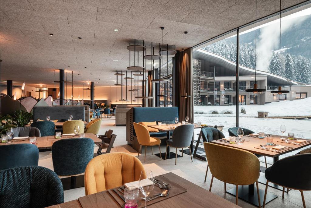un restaurant avec des tables, des chaises et des fenêtres dans l'établissement Falkensteiner Family Resort Lido Superior, à Chienes