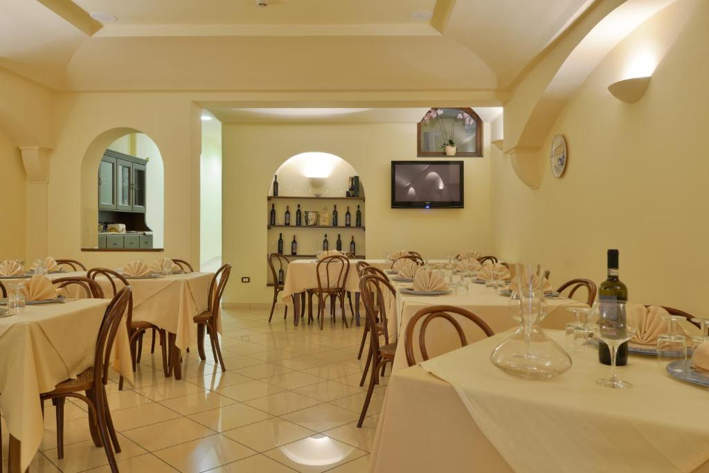 un restaurant avec des tables et des chaises blanches et une horloge dans l'établissement Hotel La Marina, à Santa Maria di Castellabate 54 autres photos