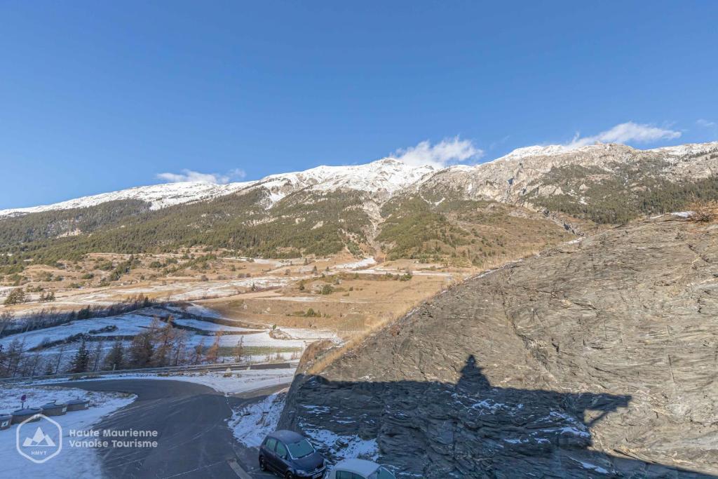 - une vue sur une montagne enneigée et une route dans l'établissement Résidence Le Pied des Pistes C6, à Lanslevillard 2 autres photos