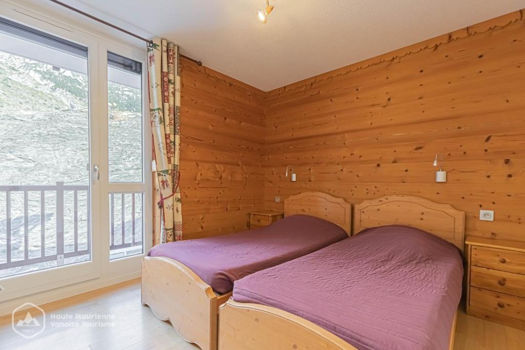 une chambre avec un lit et une grande fenêtre dans l'établissement Résidence Le Pied des Pistes C6, à Lanslevillard