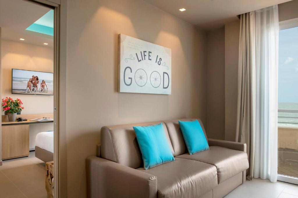 un salon avec un canapé avec des coussins bleus dans l'établissement Hotel Adlon - FRONTE MARE, à Riccione