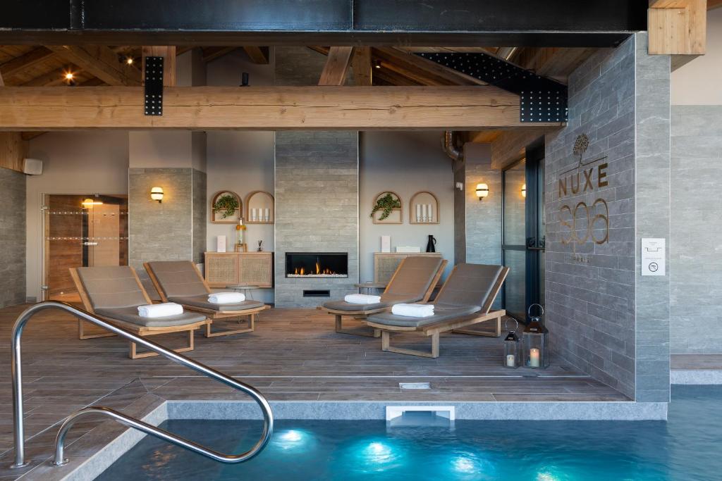 une piscine avec des chaises longues et une cheminée dans l'établissement Ours Blanc Hotel & Spa, aux Menuires