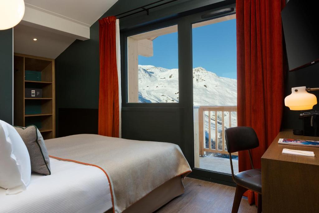 - une chambre avec un lit et une fenêtre offrant une vue sur la montagne dans l'établissement Ours Blanc Hotel & Spa, aux Menuires