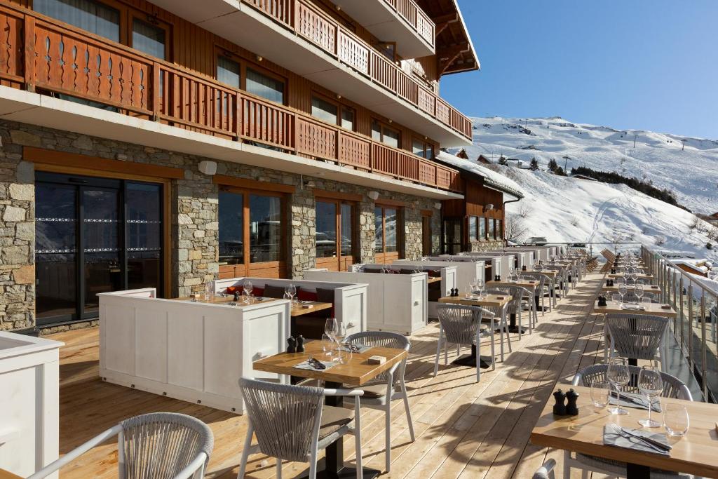 une rangée de tables et de chaises sur un bâtiment dans l'établissement Ours Blanc Hotel & Spa, aux Menuires