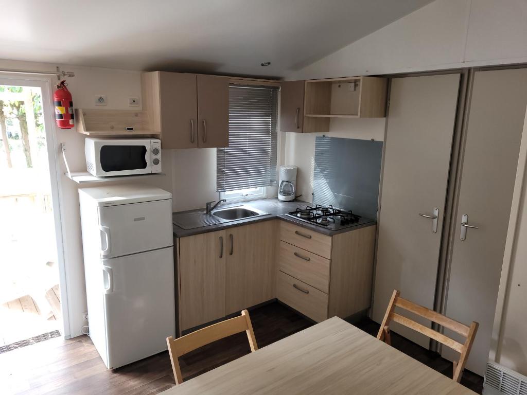 Il comprend une petite cuisine équipée d'un réfrigérateur blanc et d'un four micro-ondes. dans l'établissement Camping des septs fonts, à Agde