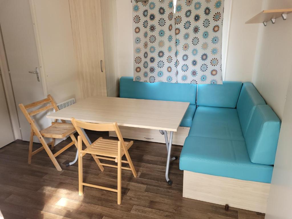 un salon avec un canapé bleu, une table et des chaises dans l'établissement Camping des septs fonts, à Agde