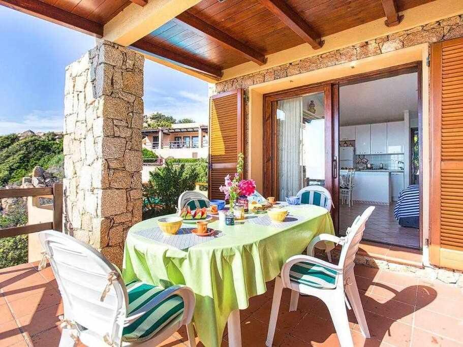 - une table avec une nappe et des chaises vertes sur la terrasse dans l'établissement Costa Paradiso villa con piscina indipendente e vista mare per 6 persone, à Costa Paradiso