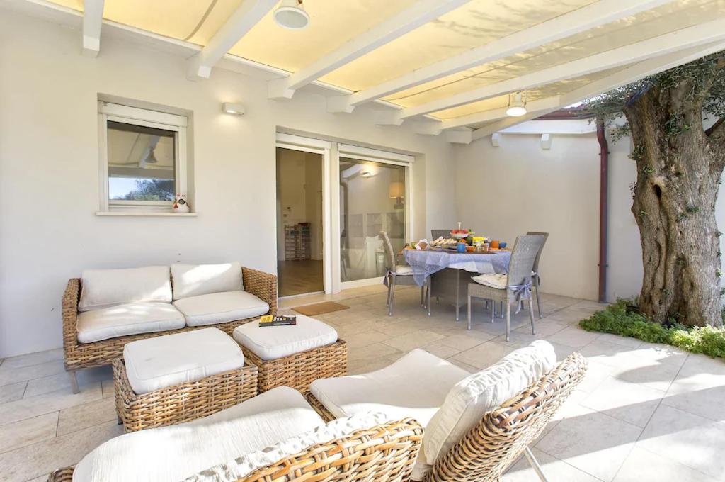 d'une terrasse avec des chaises en osier, une table et un arbre. dans l'établissement Alghero Villa Nuit Blanche con piscina Air Co WiFi vicino spiaggia, à Alghero