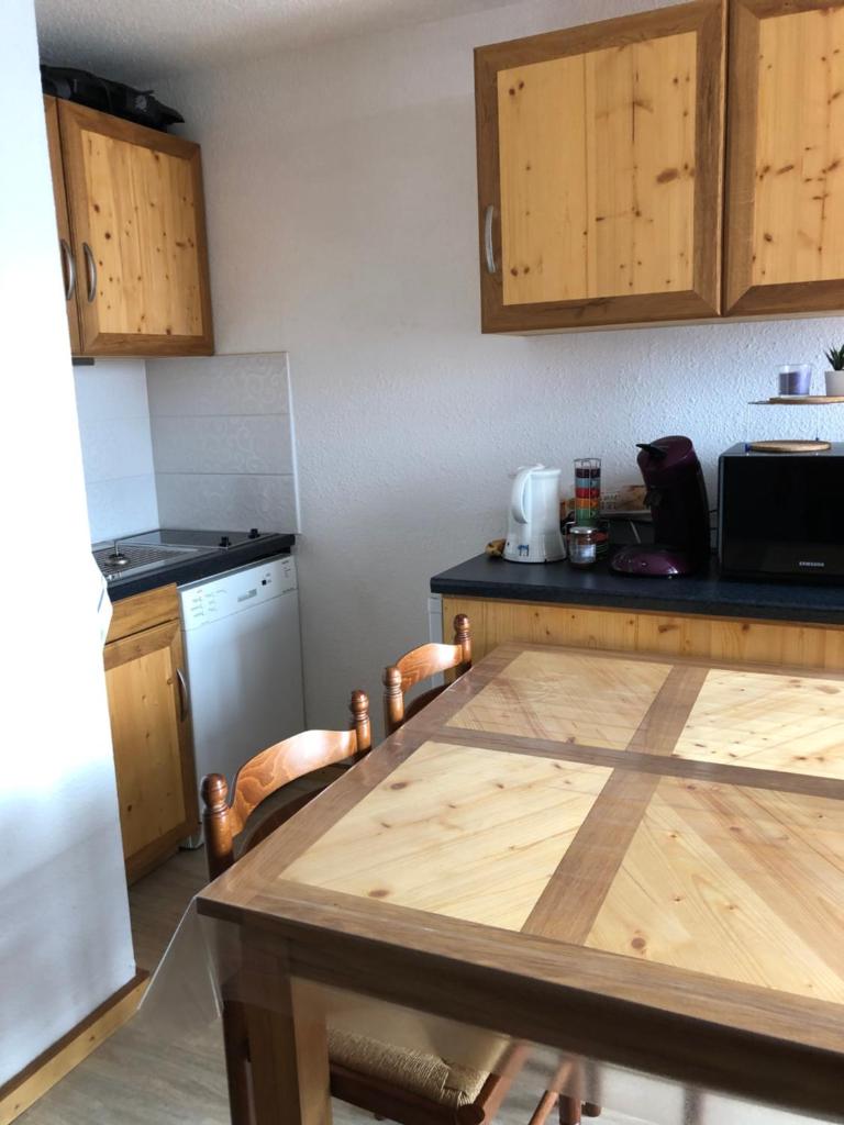 une cuisine avec une table en bois et un micro-ondes dans l'établissement Petit appartement Labellisé Les 2 Alpes résidence Arc en Ciel télésiège Petite Aiguille, à Les Deux Alpes