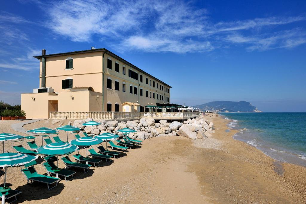 - une plage avec des chaises, un bâtiment et l'océan dans l'établissement Hotel Brigantino Non Dista, à Porto Recanati
