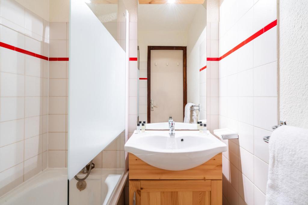 une salle de bain avec un lavabo et une baignoire et un lavabo dans l'établissement Vacancéole - Résidence Grand Morillon, à Morillon
