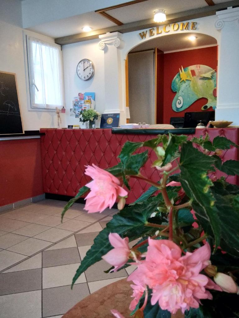 un hall avec une salle d'attente ornée de fleurs roses dans l'établissement Villa Romana, à Lignano Sabbiadoro