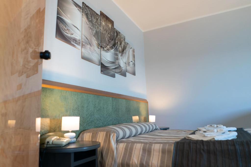 une chambre d'hôtel avec un lit et deux photos sur le mur dans l'établissement Hotel Melissa, à Torre Melissa