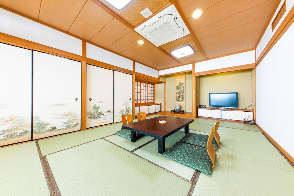 un salon avec une table et une télévision dans l'établissement Umino Hotel Hajime, à Beppu