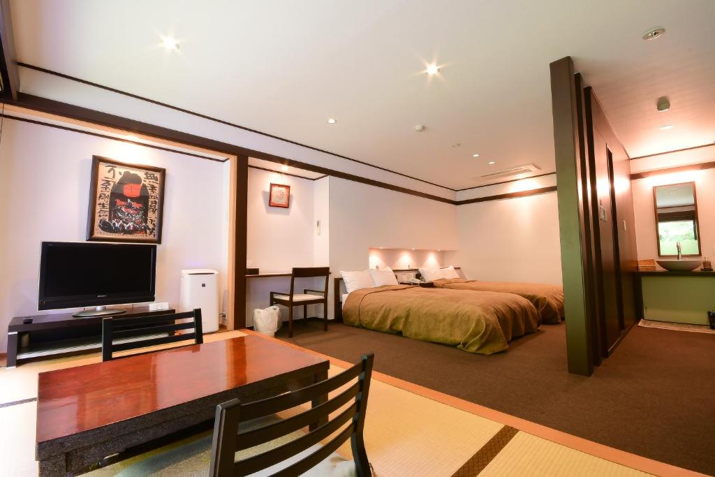 une chambre avec un lit, un bureau et une télévision dans l'établissement Koyasan Shukubo Fumonin, à Koyasan 37 autres photos