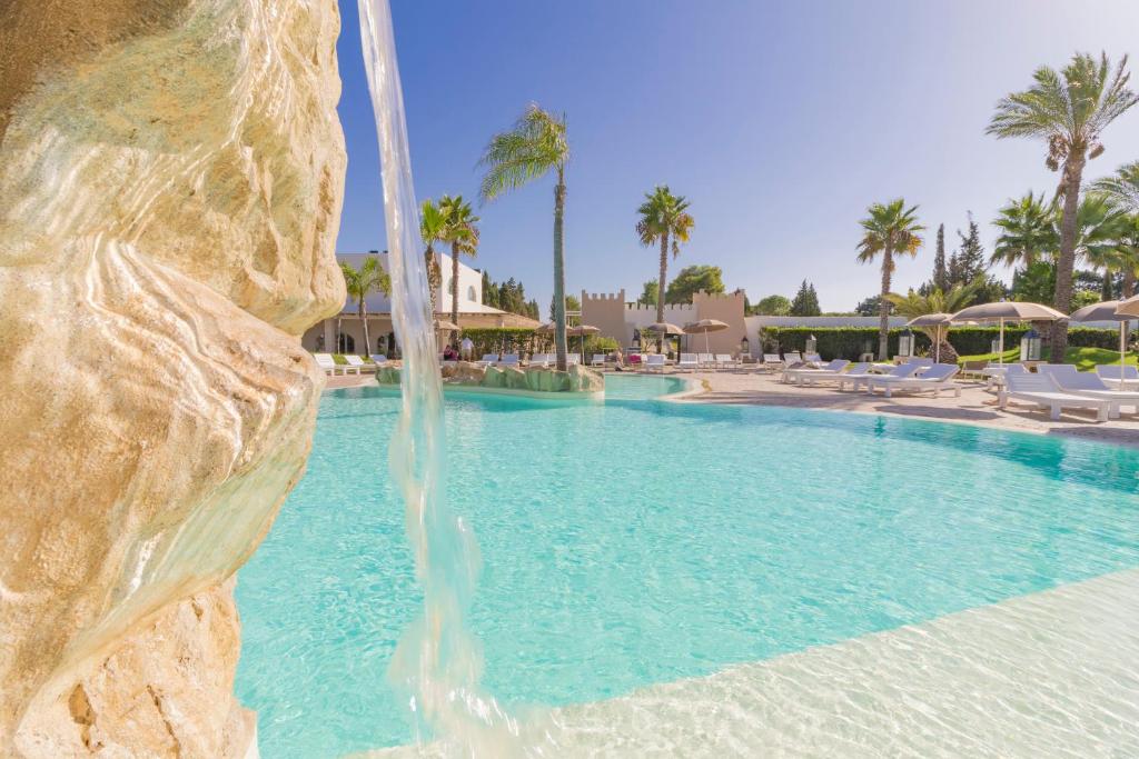 une piscine avec cascade dans un complexe hôtelier dans l'établissement HOTEL BARONE DI MARE, à Torre dell'Orso