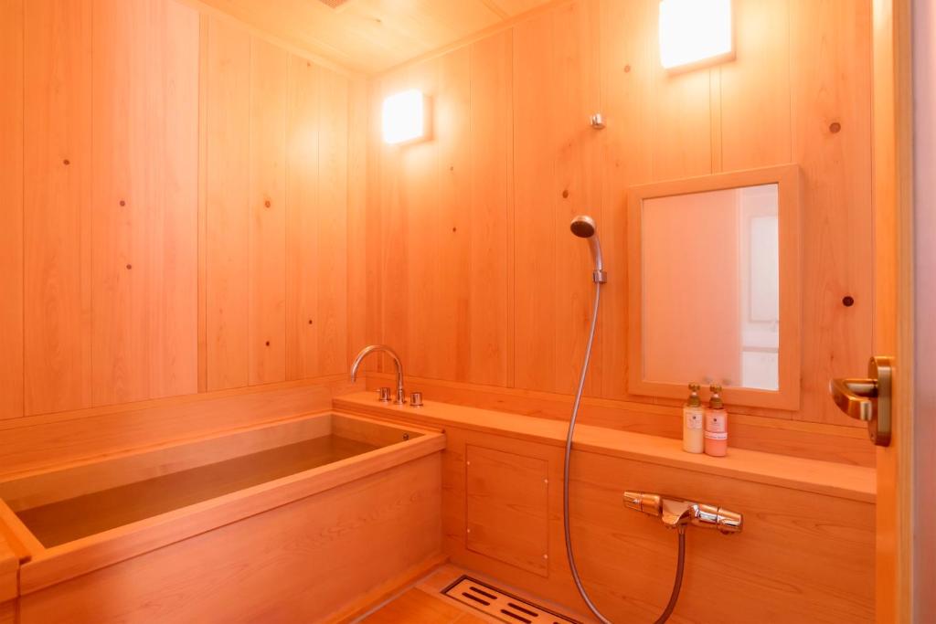 La salle de bains est pourvue d'une baignoire, d'une douche et d'un miroir. dans l'établissement Koyasan Shukubo Fumonin, à Koyasan