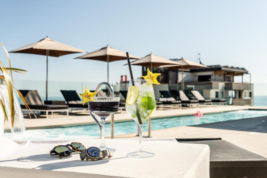 2 verres sur une table à côté d'une piscine dans l'établissement Bellini Relais, à Lignano Sabbiadoro