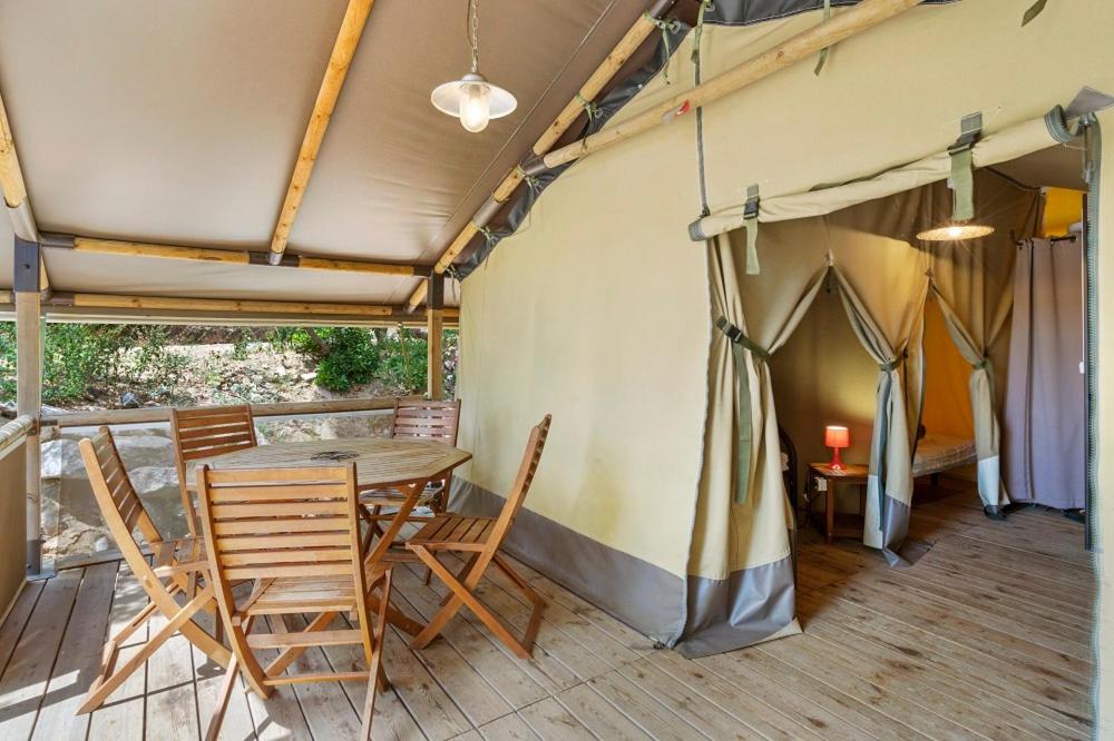 une tente avec une table et des chaises sur une terrasse dans l'établissement Camping Le Damier, à Pianottoli-Caldarello