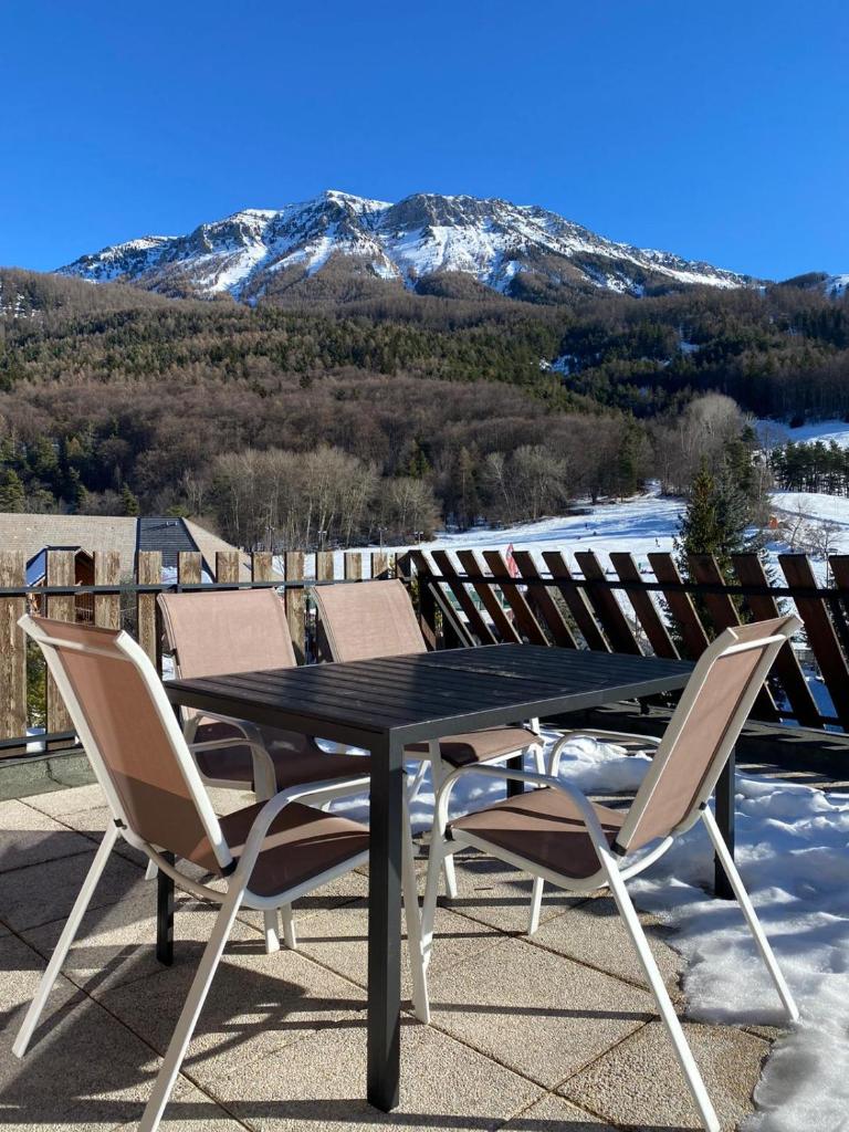 une table et des chaises sur un toit recouvert de neige dans l'établissement Montclar Appart 4 à 6 places - terrasse vue panoramique - idéalement situé, à Montclar