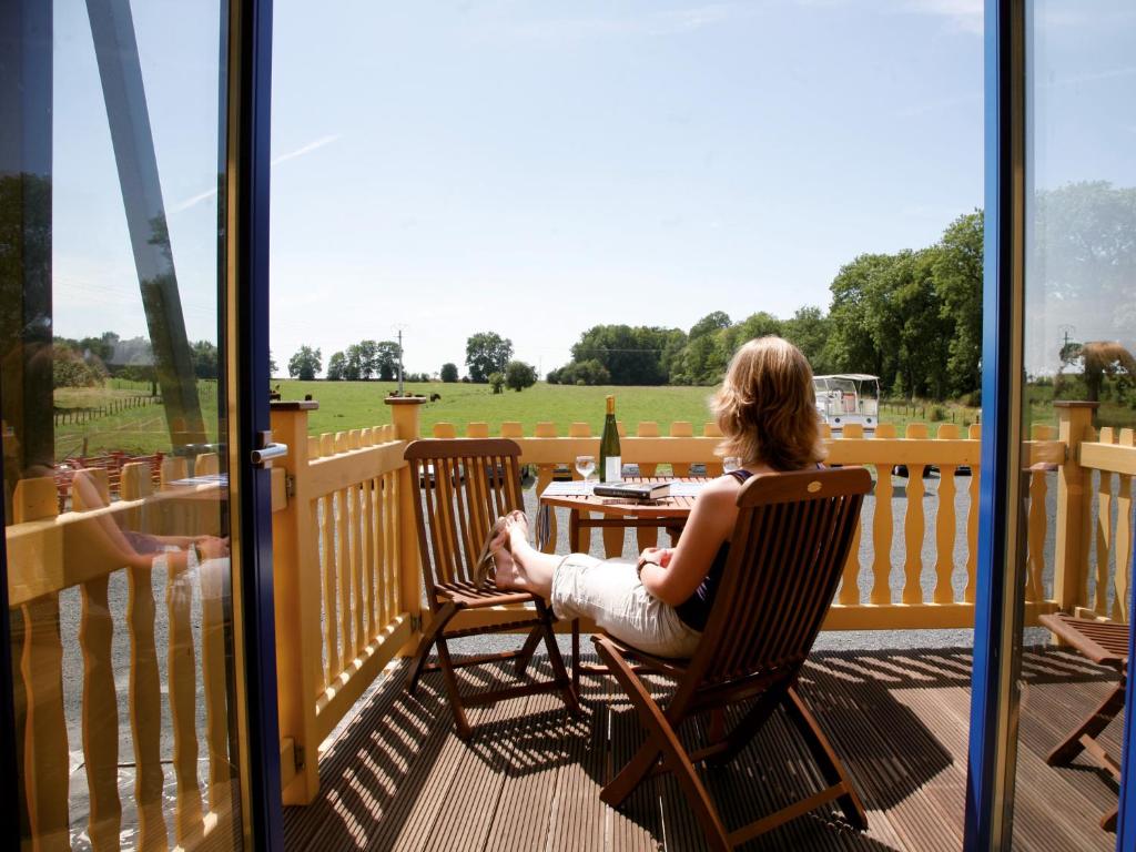 une femme assise sur une chaise sur une terrasse avec une table dans l'établissement Kuhnle-Tours Niderviller, à Niderviller 11 autres photos