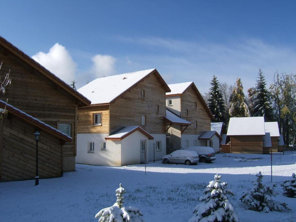 un groupe de maisons avec de la neige au sol dans l'établissement T3 coquet et lumineux aux pieds des pistes, à Ancelle