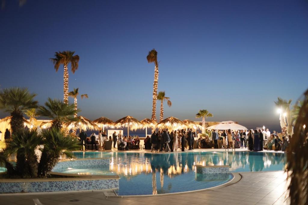 un groupe de personnes autour d'une piscine bordée de palmiers dans l'établissement MOOD Sea Stage, à Castiglione