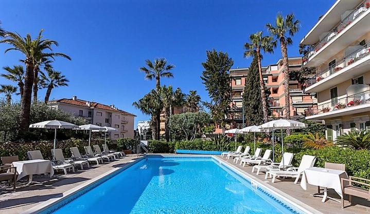 une piscine avec chaises et parasols à côté d'un bâtiment dans l'établissement Hotel Paradiso, à Sanremo