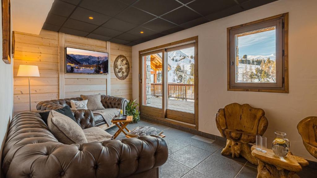 - un salon avec un canapé en cuir et des fenêtres dans l'établissement Hôtel Carlina by Les Etincelles, à Belle Plagne