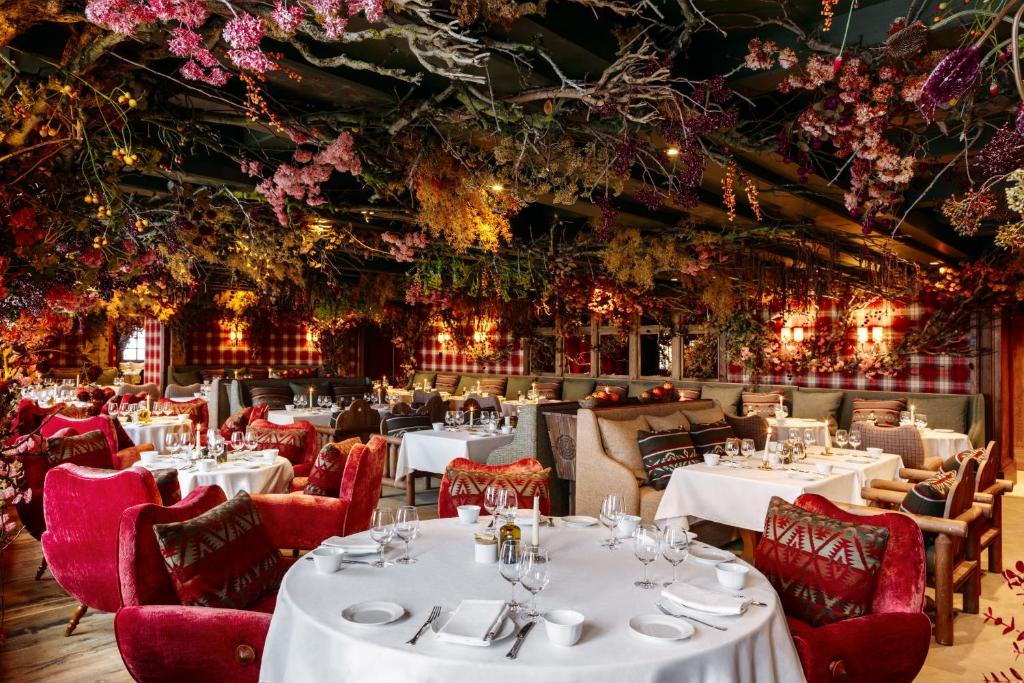 - un restaurant avec des tables, des chaises et des fleurs au plafond dans l'établissement Airelles Val d'Isère, à Val dʼIsère