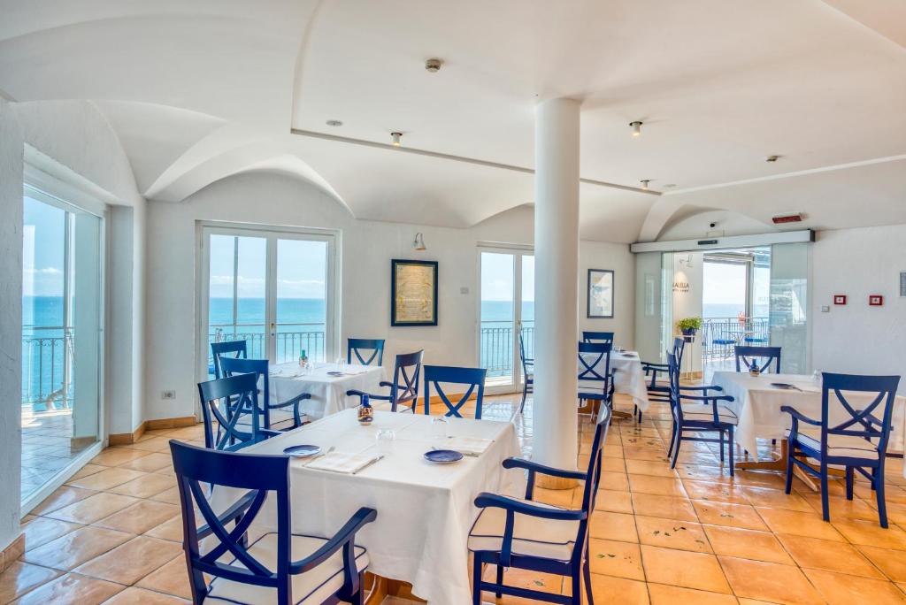 une salle à manger avec des tables et des chaises et l'océan dans l'établissement Hotel Cetus, à Cetara