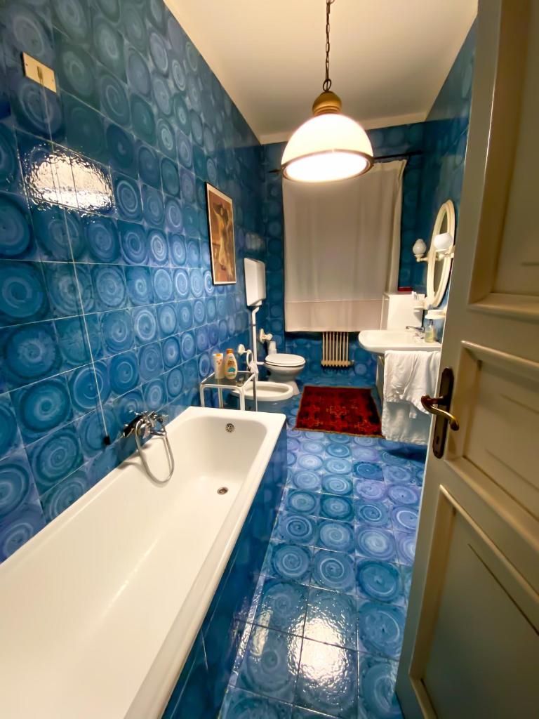 - une salle de bains bleue avec 2 toilettes et une baignoire dans l'établissement Villa con vista lago e piscina, à Moniga del Garda