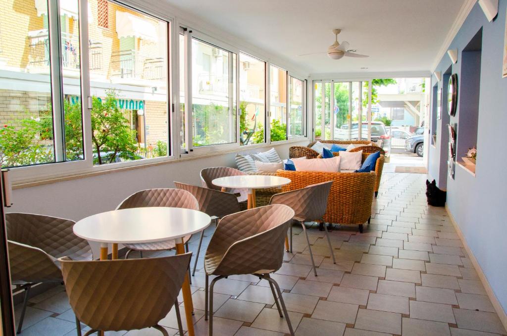 un restaurant avec des tables, des chaises et des fenêtres dans l'établissement Hotel Stella Alpina, à Rimini