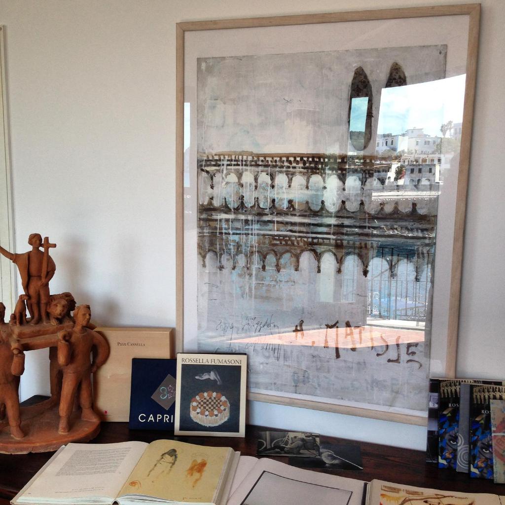 une table avec des livres et une photo sur le mur dans l'établissement Hotel Umberto A Mare, à Ischia