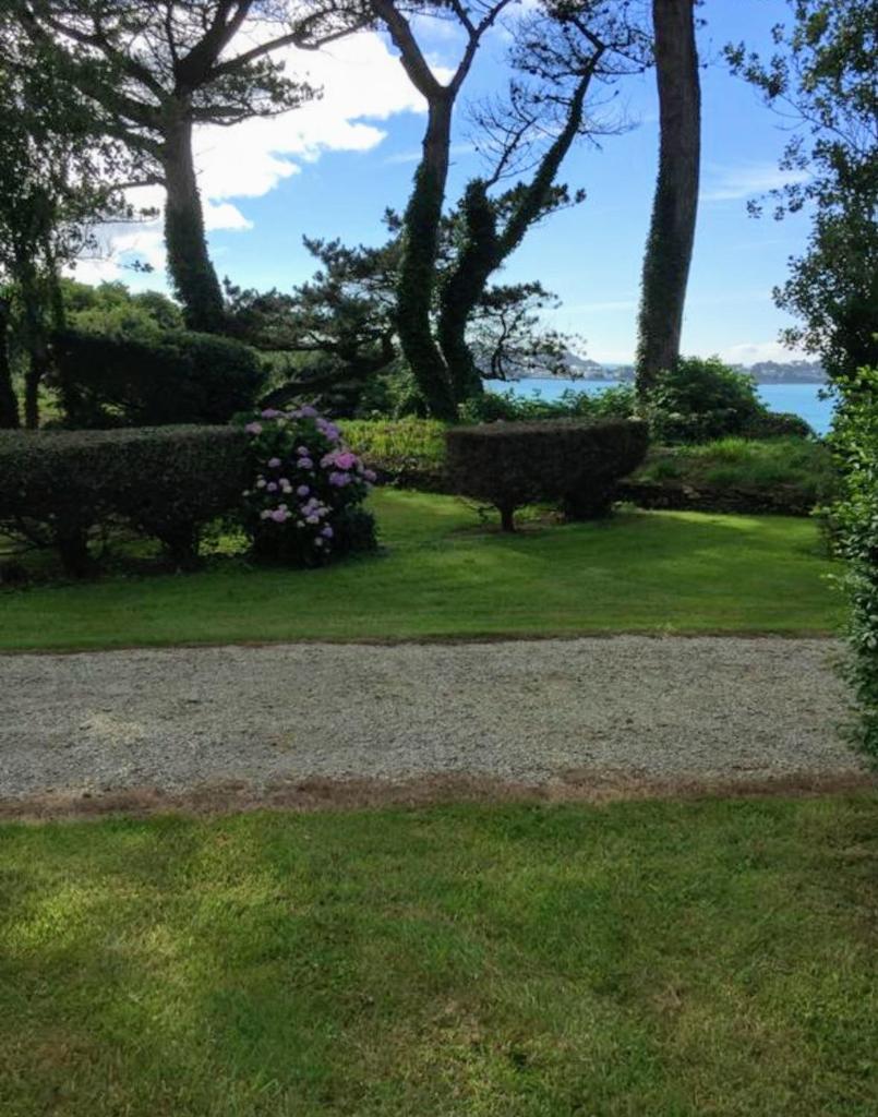 un parc avec des bancs et des fleurs dans l'herbe dans l'établissement Tente 3 chambres, petit camping familial vue mer, à Plestin-les-Grèves