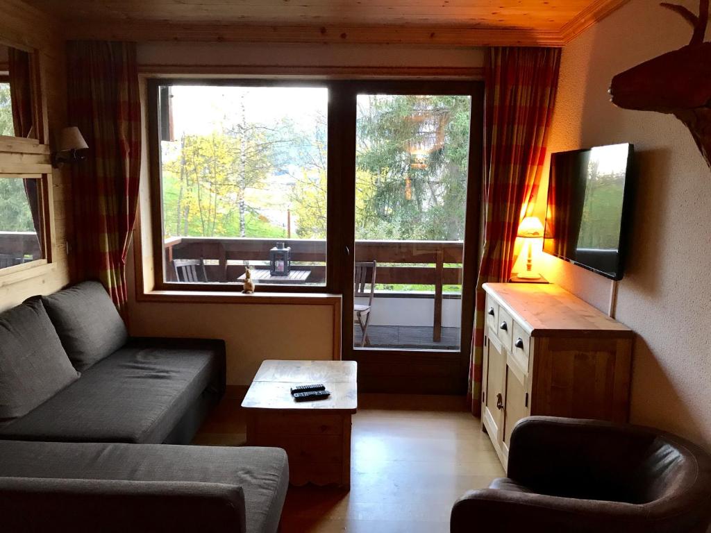 un salon avec un canapé et une grande fenêtre dans l'établissement Megève - Appartement 2 chambres - Proche Centre et Pistes - Fibre - Parking, à Megève