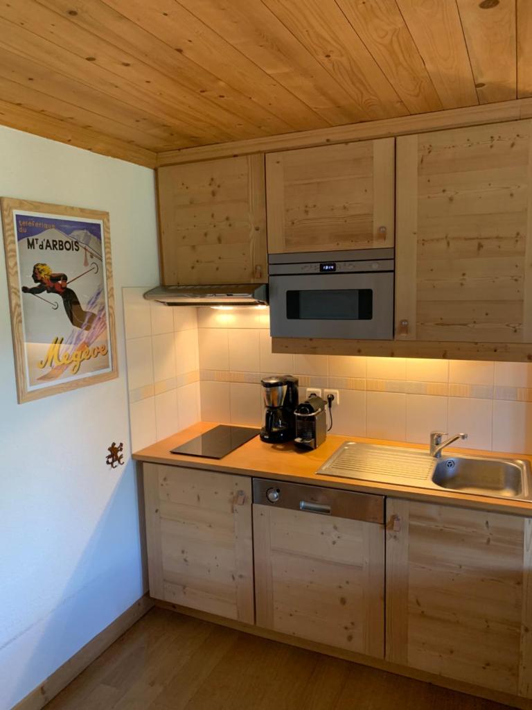 une cuisine avec des armoires en bois et un comptoir dans l'établissement Megève - Appartement 2 chambres - Proche Centre et Pistes - Fibre - Parking, à Megève