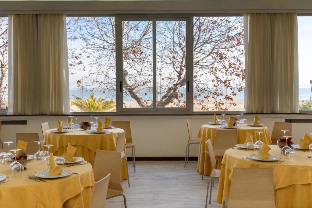 une salle à manger avec tables, chaises et fenêtres dans l'établissement Hotel Royal, à Giulianova 36 autres photos