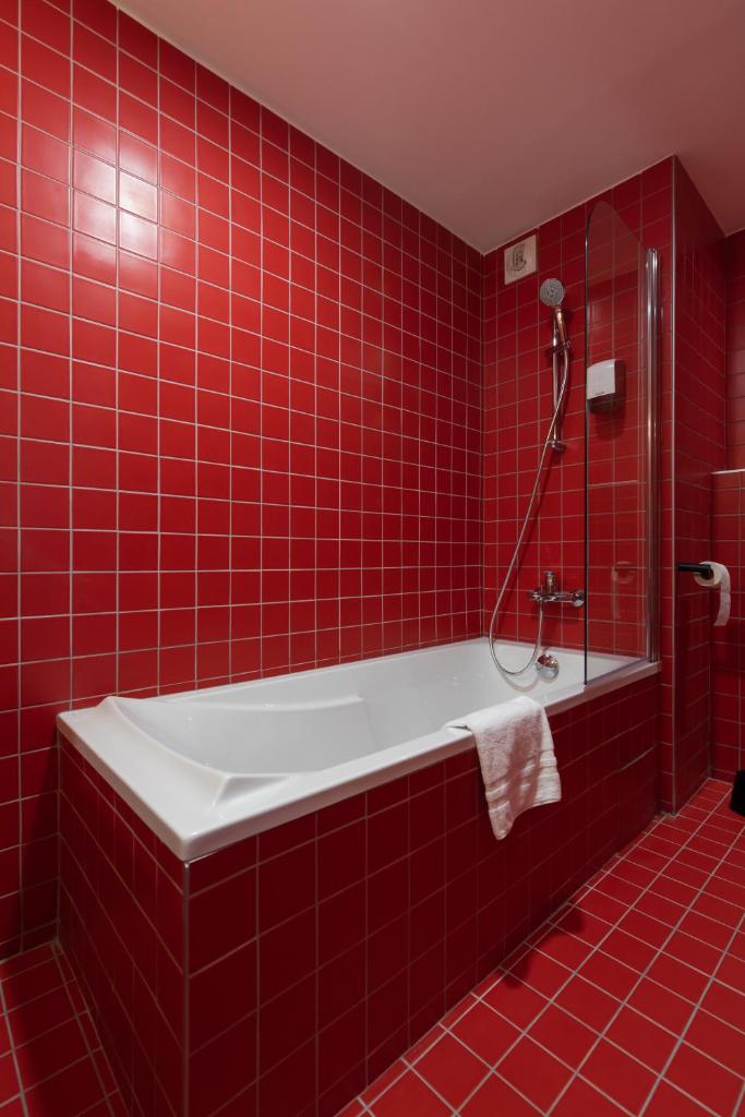 La salle de bains est pourvue de carrelage rouge, d'une baignoire et d'une douche. dans l'établissement SUNWEB - Timberlodge, à Oz
