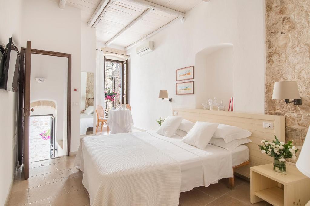 une chambre blanche avec un lit et une table dans l'établissement Hotel Corte Altavilla, à Conversano