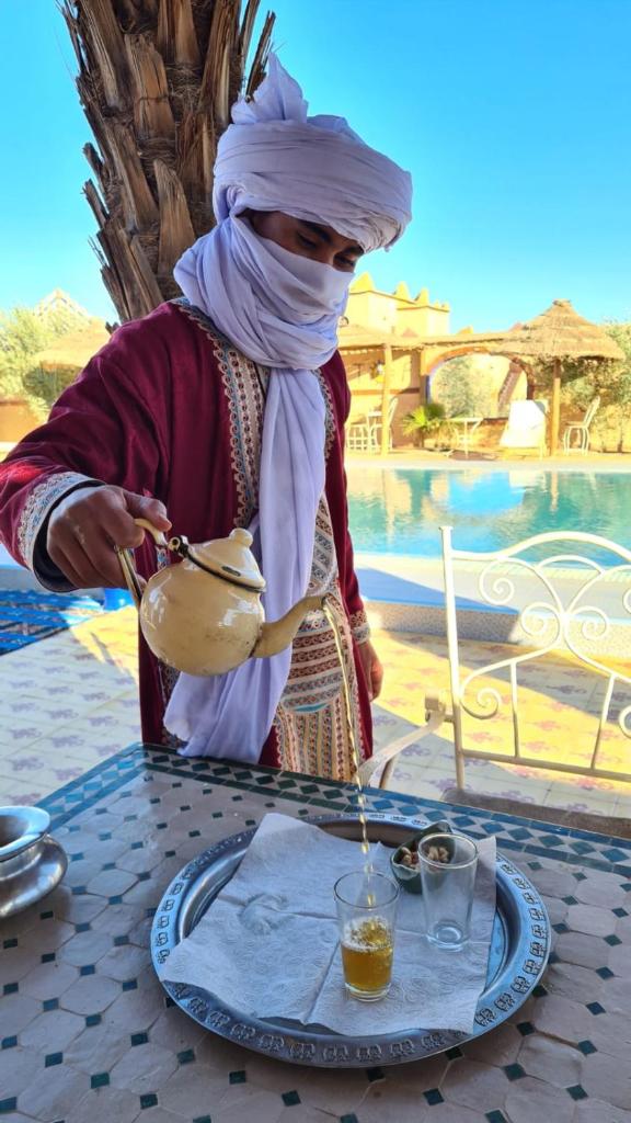 une femme est debout à une table avec un verre dans l'établissement Dar Tafouyte, à Merzouga
