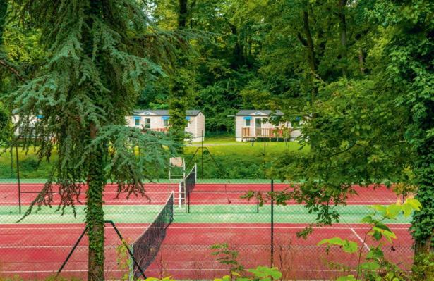 - un ensemble de courts de tennis avec des arbres et des maisons dans l'établissement Mobil Home 6 personnes, à Saint-Chéron