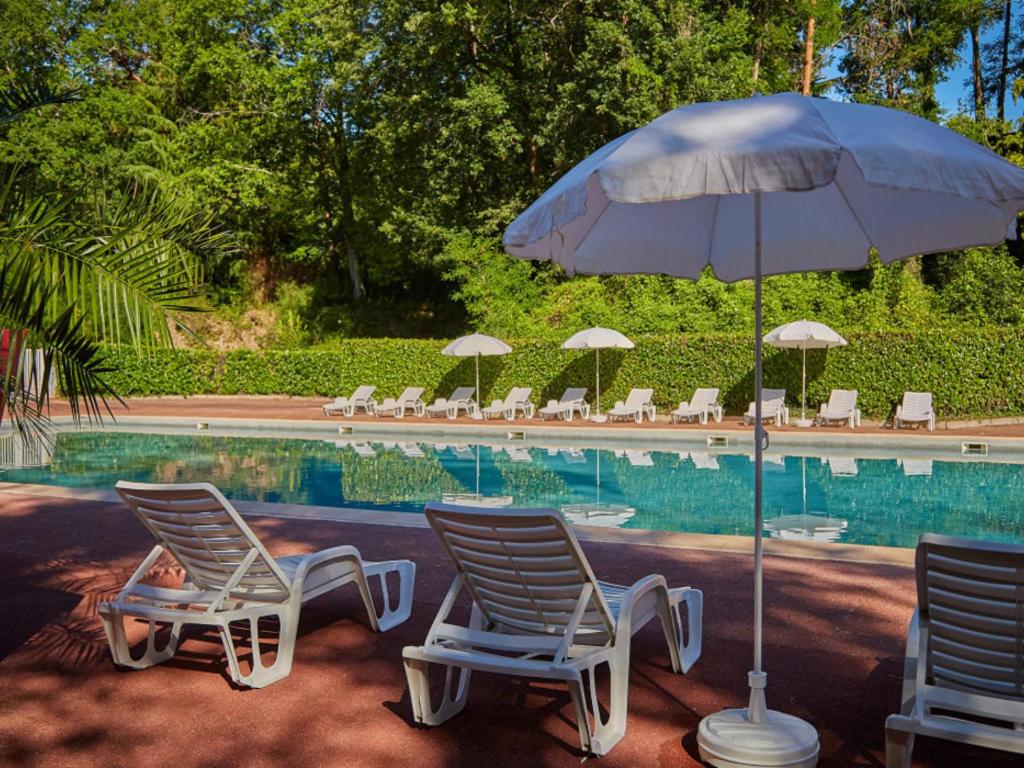deux chaises et un parasol à côté d'une piscine dans l'établissement Mobil Home 6 personnes, à Saint-Chéron